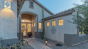 A building with a stucco exterior, a decorative wall mural, and a pathway leading to the entrance.