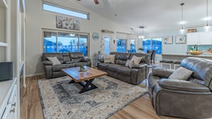 A spacious living room with leather sofas, a coffee table, and a ceiling fan.