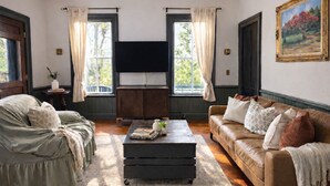 Ein Wohnzimmer mit einer Couch, einem Couchtisch, einem Fernseher und einem Bild an der Wand.