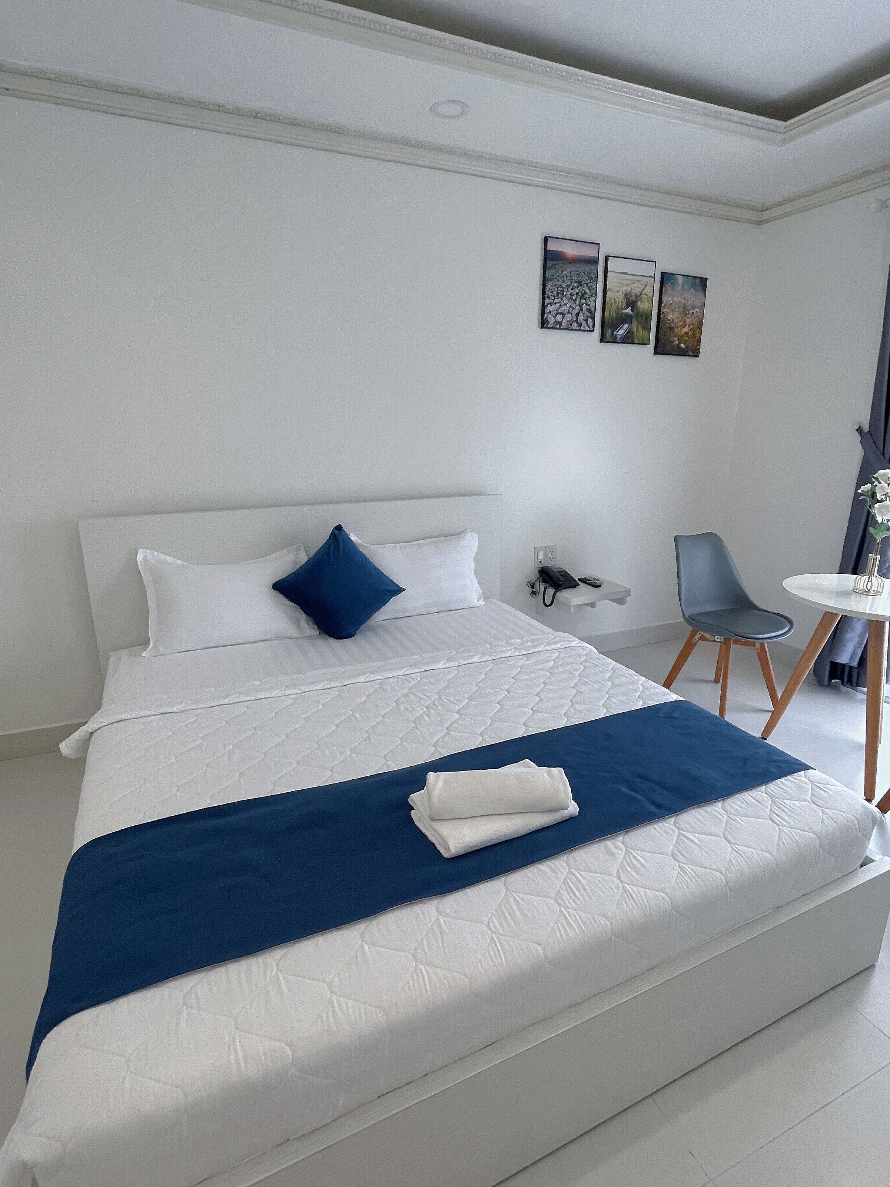 A hotel room with a large bed, a desk, and a chair.