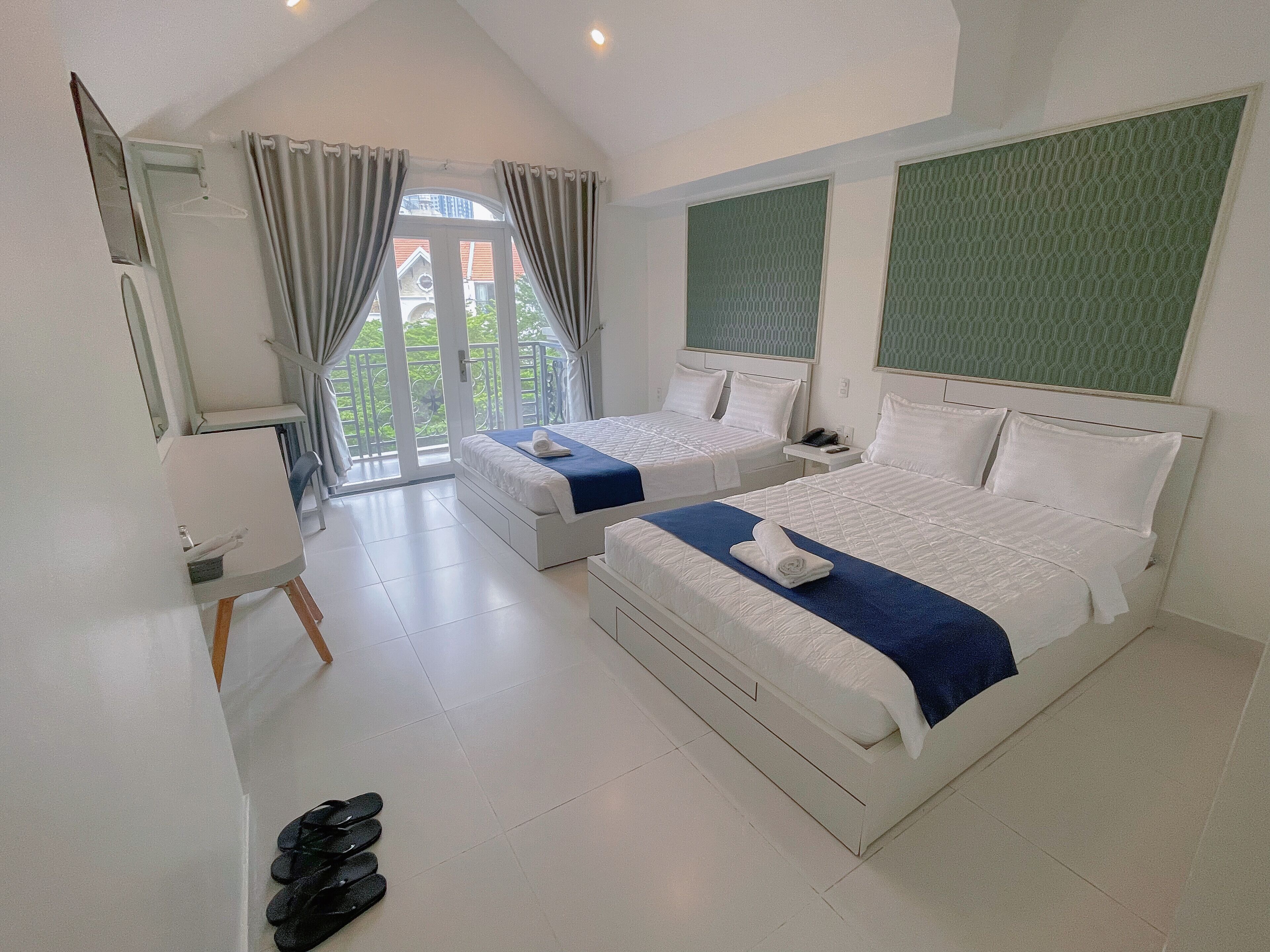 A hotel room with two beds, a balcony, and a large window.