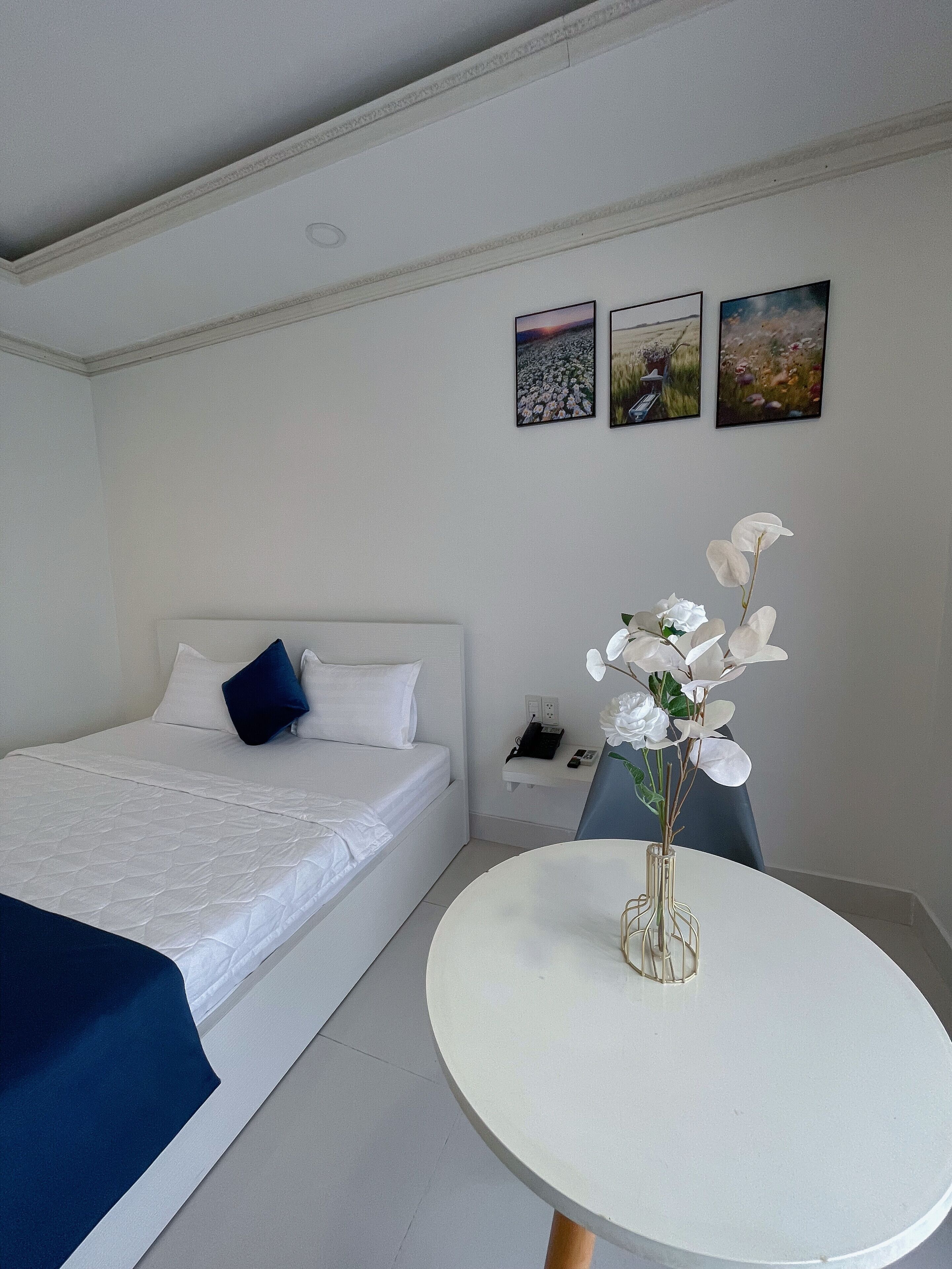 A bedroom with a bed, bedside table, and a wall-mounted phone.