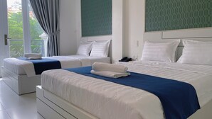 Habitación de hotel con dos camas, un balcón y un teléfono en la mesita de noche.