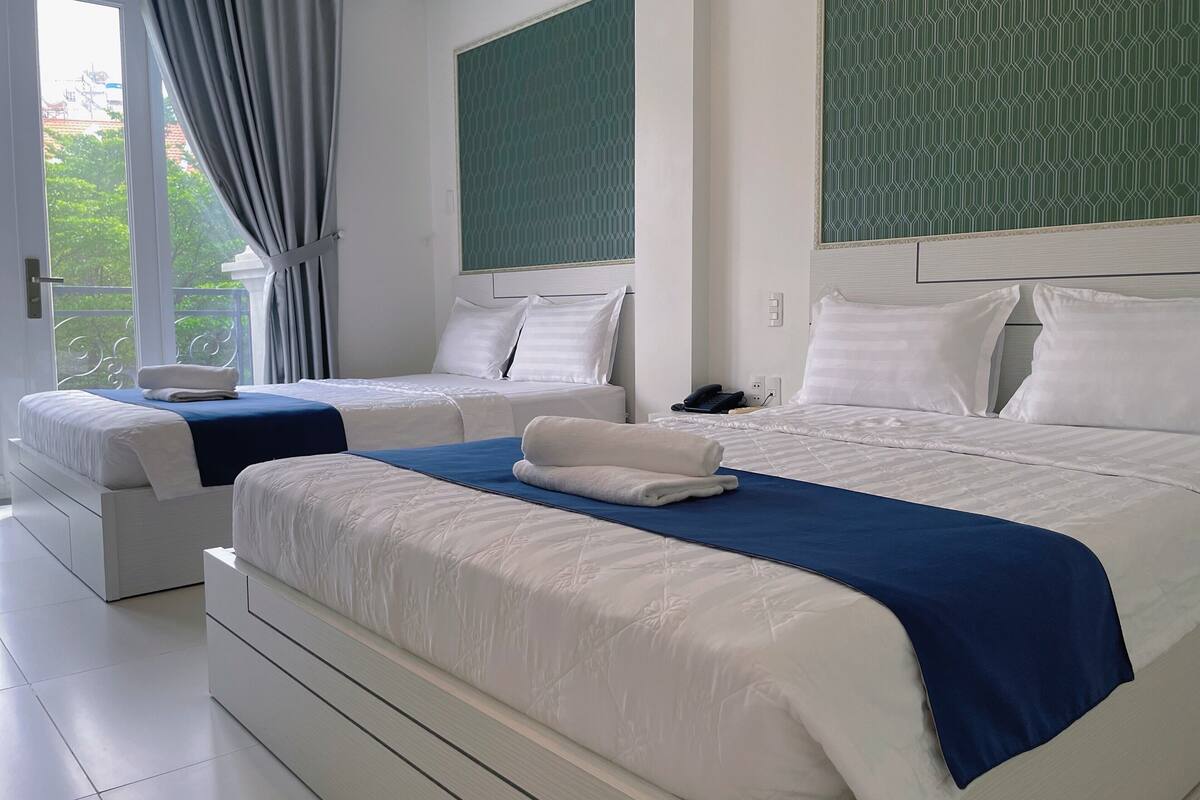 A hotel room with two beds, a balcony, and a phone on the nightstand.