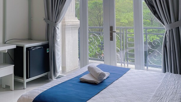 Una habitación de hotel con cama, escritorio y balcón con cortinas.