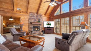 Ein gemütliches Blockhaus-Interieur mit Kamin, Ledersofas und einem Fernseher.