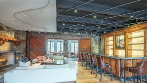A spacious living area with a fireplace, a bar with stools, and a large sofa. - Alpine Lodging Telluride Ski Resort (Telluride)