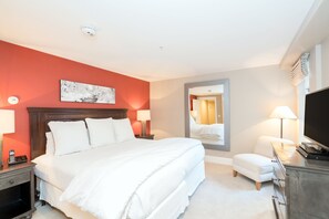 A hotel room with a large bed, a bedside table with a lamp, a TV, and a small seating area. - Alpine Lodging Telluride Ski Resort (Telluride)