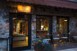 A stone building with a sign reading "River Club Tequila." Inside, there are wooden tables and chairs, and a bar area is visible through the glass doors.