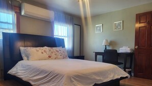 A neatly made bed with floral pillows, a wooden headboard, and a bedside table with a lamp. - 5 Beds 2 Bathroom Appartment (Cambridge)
