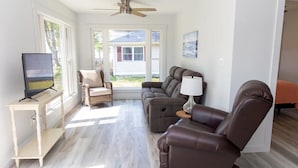 A living room with a sofa, armchair, and TV on a stand.