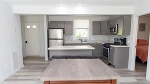 A modern kitchen with grey cabinets, stainless steel appliances, and a central island with seating.