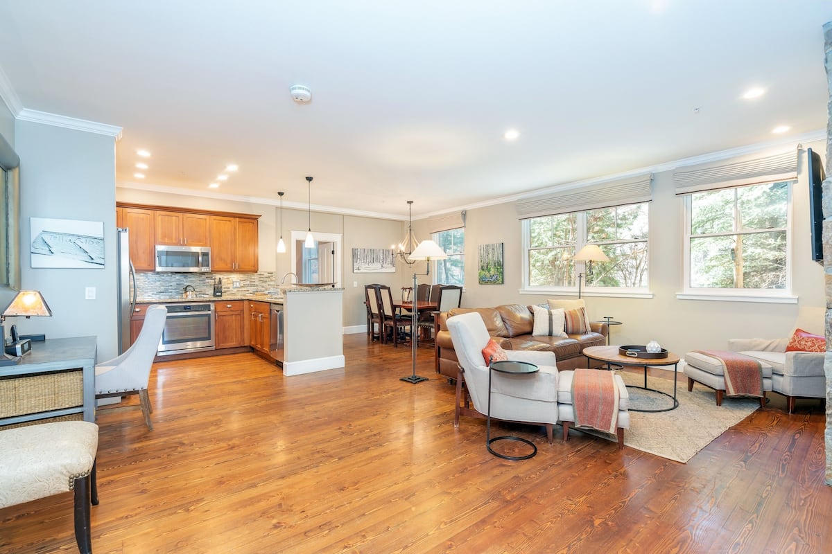 A spacious living area with hardwood flooring, a kitchen with wooden cabinets, and a dining area with a table and chairs.
