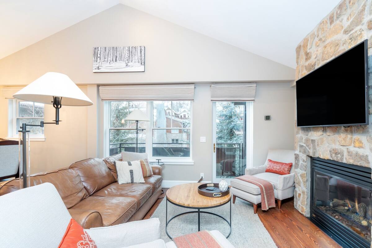 A living room with a stone fireplace, leather sofa, and a round coffee table.