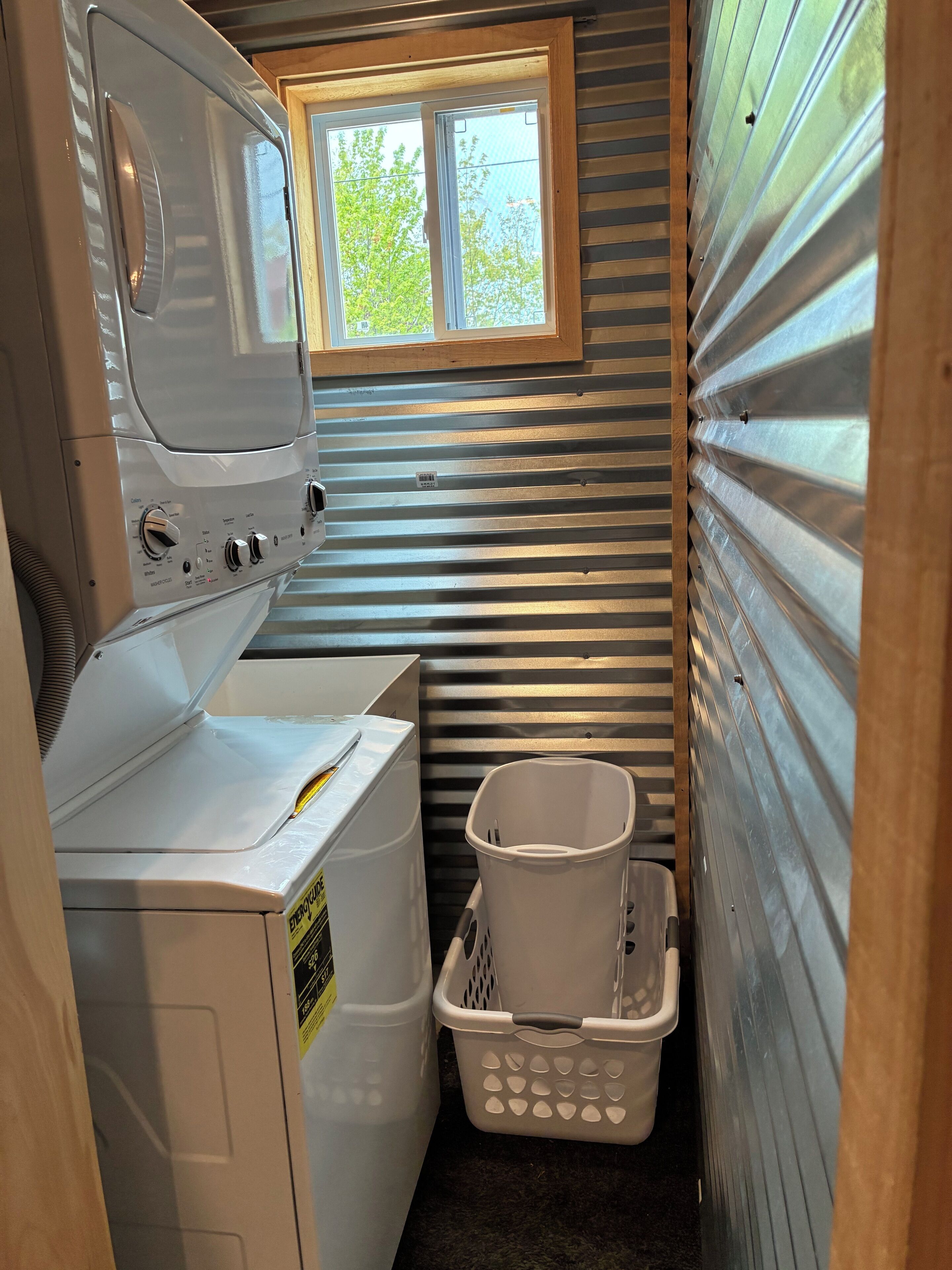 A compact laundry room with a washer and dryer, a window, and a laundry basket.