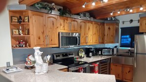 A kitchen with wooden cabinets, a granite countertop, stainless steel appliances, and a small island with bar stools. - Modern Contemporary Condo-Tahoe Lodge Atmosphere in Incline Village, NV. (Incline Village)