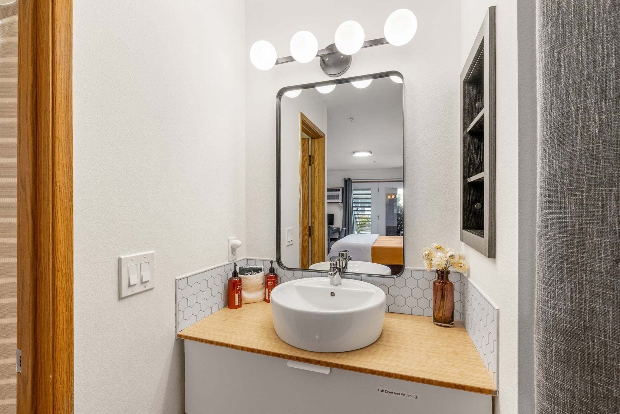 Een badkamer met een witte wastafel, opbergmeubel en een spiegel met verlichting.