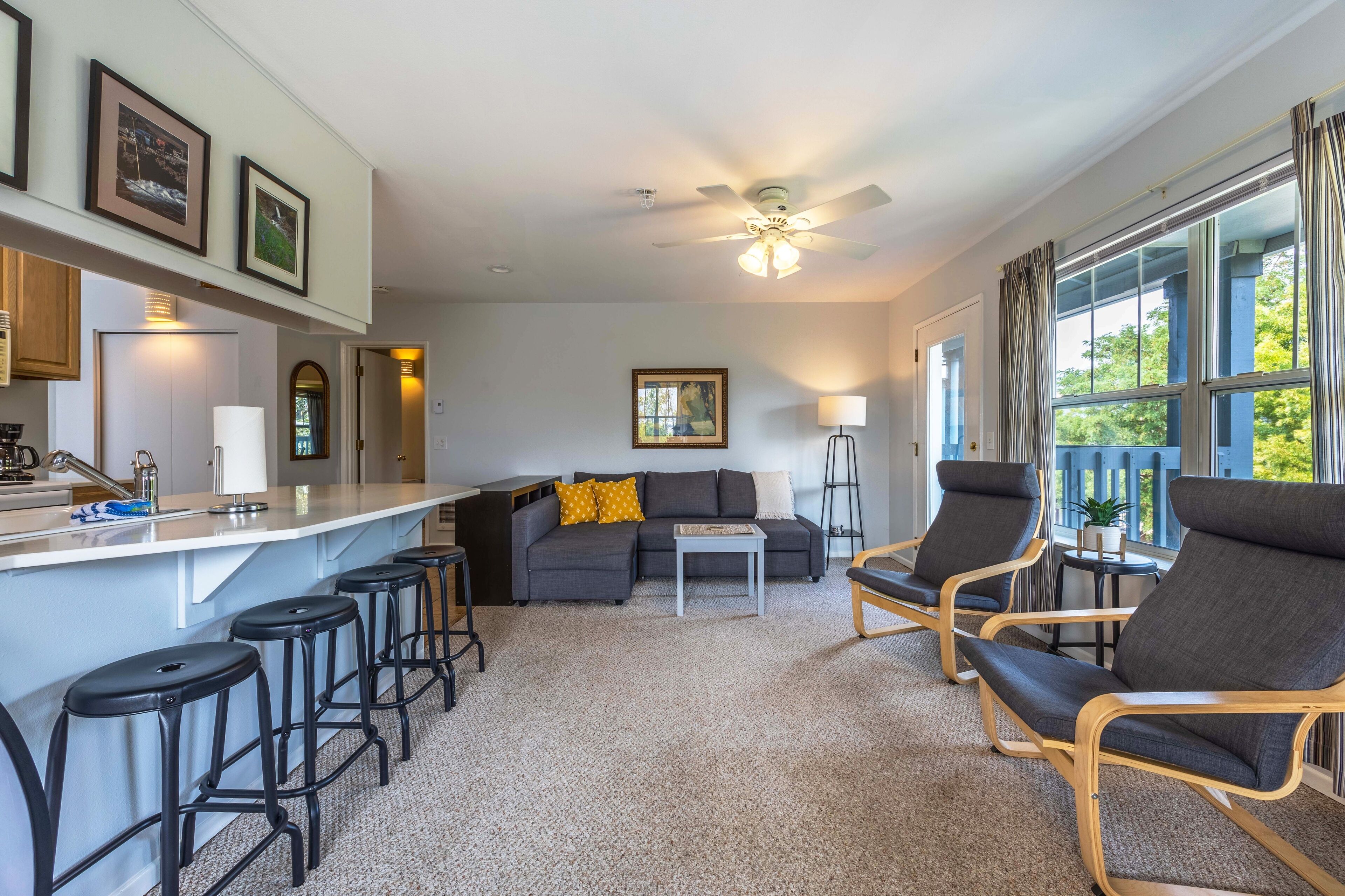 A modern living room with a sofa, chairs, a coffee table, and a bar area with stools.