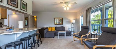 A modern living room with a sofa, chairs, a coffee table, and a bar area with stools.