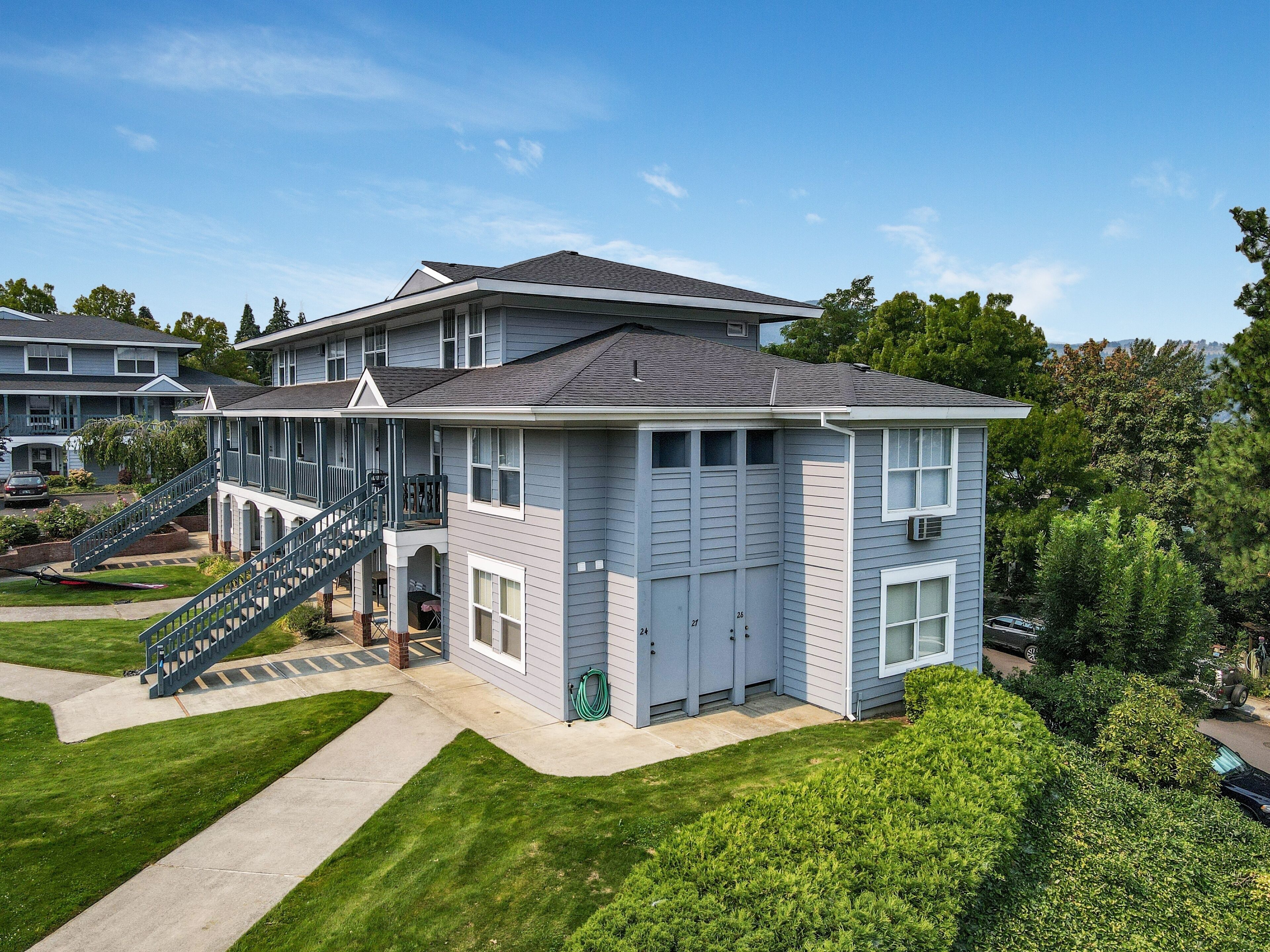 A two-story residential building with a covered porch and a staircase leading to the upper floor.