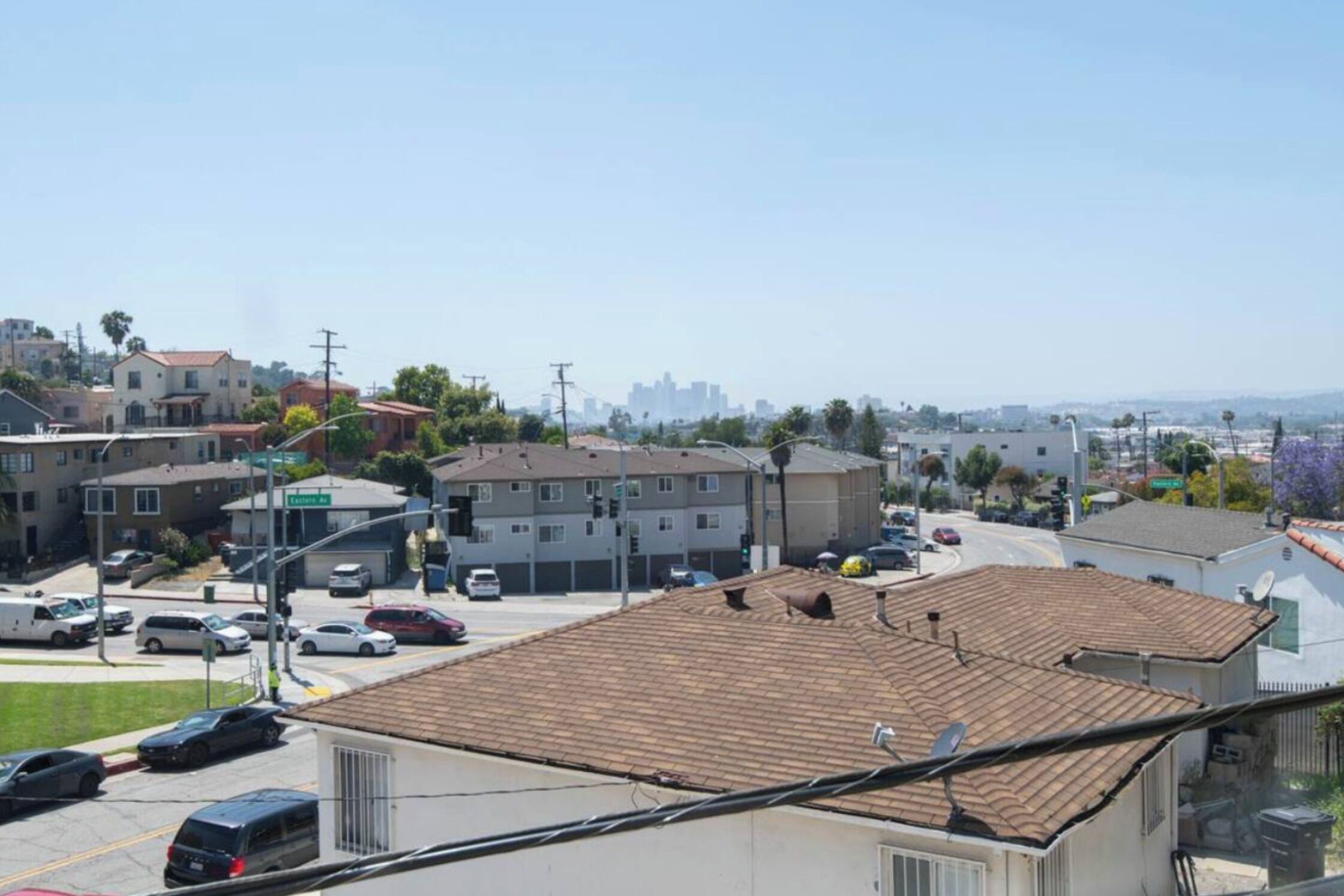 A residential area with houses, a street, and a distant city skyline.