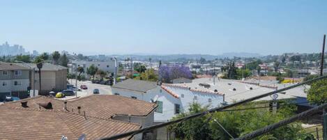 Zona residencial con vista despejada a un horizonte urbano distante, un estacionamiento y un edificio con tejado de baldosas.