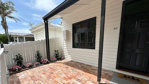 A house with a covered patio area, a white fence, and a black door. - Walking distance to train stations, sporting venues and parks (Hamilton)
