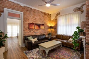 A living room with a brick wall, leather sofas, a coffee table, and a patterned rug. - Walking distance to train stations, sporting venues and parks (Hamilton)
