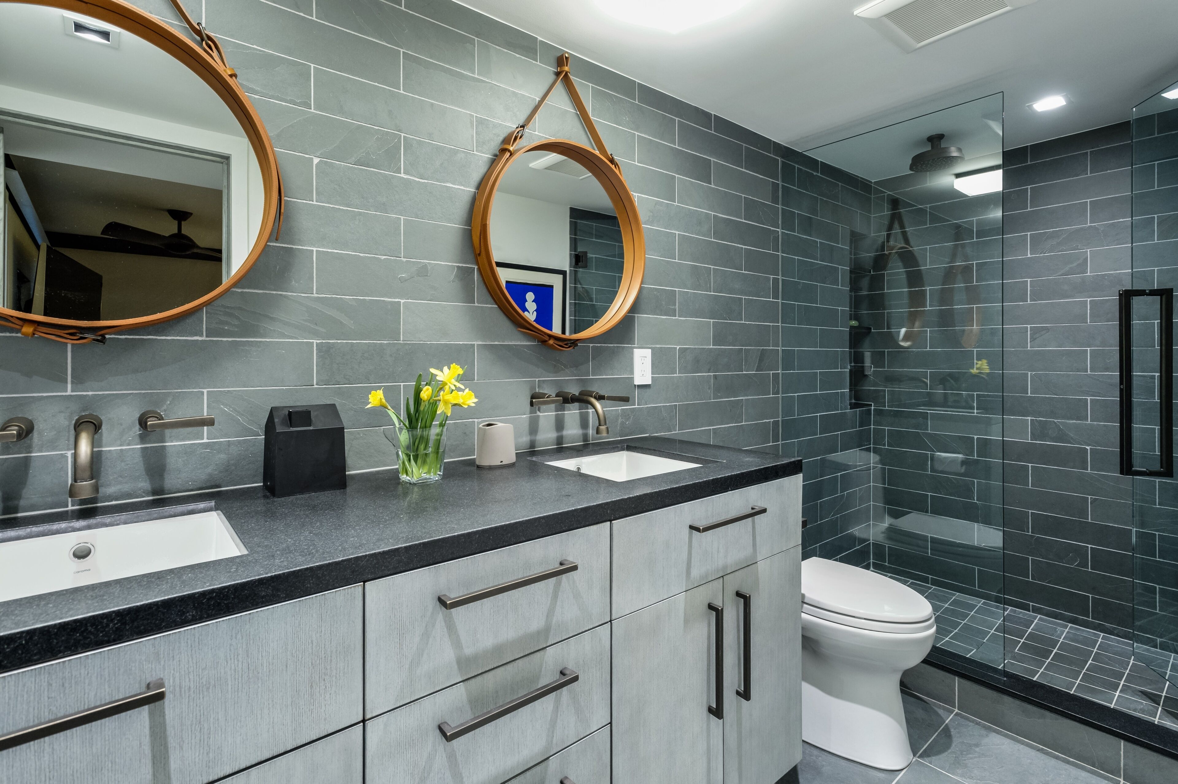 A modern bathroom with two sinks, a toilet, and a shower.