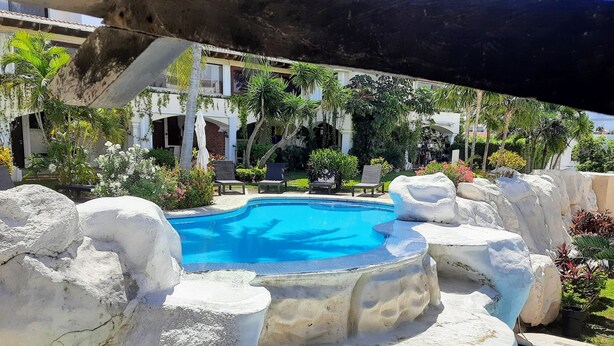 A pool with a waterfall feature, surrounded by rock formations and palm trees. - Cancún Energy, Tulum Spirit  Luxe & Private Stay (Cancún)