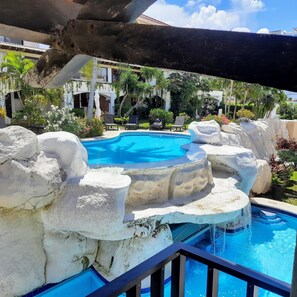 A pool with a waterfall feature, surrounded by rock formations and palm trees.