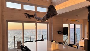 Un comedor con vista al mar, techo de madera y una amplia mesa con velas.