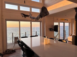 Un comedor con vista al mar, techo de madera y una amplia mesa con velas.