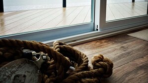 Habitación con un ventanal grande que da a una masa de agua, piso de madera y una cuerda en el suelo.