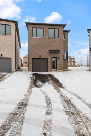 A modern two-story residential building with a garage, a driveway, and a snow-covered ground. - Newly Built Basement Suite – Comfort & Convenience (Markham)
