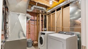 A laundry room with two washing machines, insulation, ductwork, and a wooden door labeled "DRYER". - Newly Built Basement Suite – Comfort & Convenience (Markham)