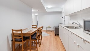 A compact kitchen with white cabinets, a dining table with chairs, and a small island. - Newly Built Basement Suite – Comfort & Convenience (Markham)