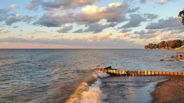 A beach with waves, a wooden jetty, and a distant shoreline with trees. - LakePointe Shores # 7 Welcoming 3-bedroom cottage in Madison on the Lake (Madison)