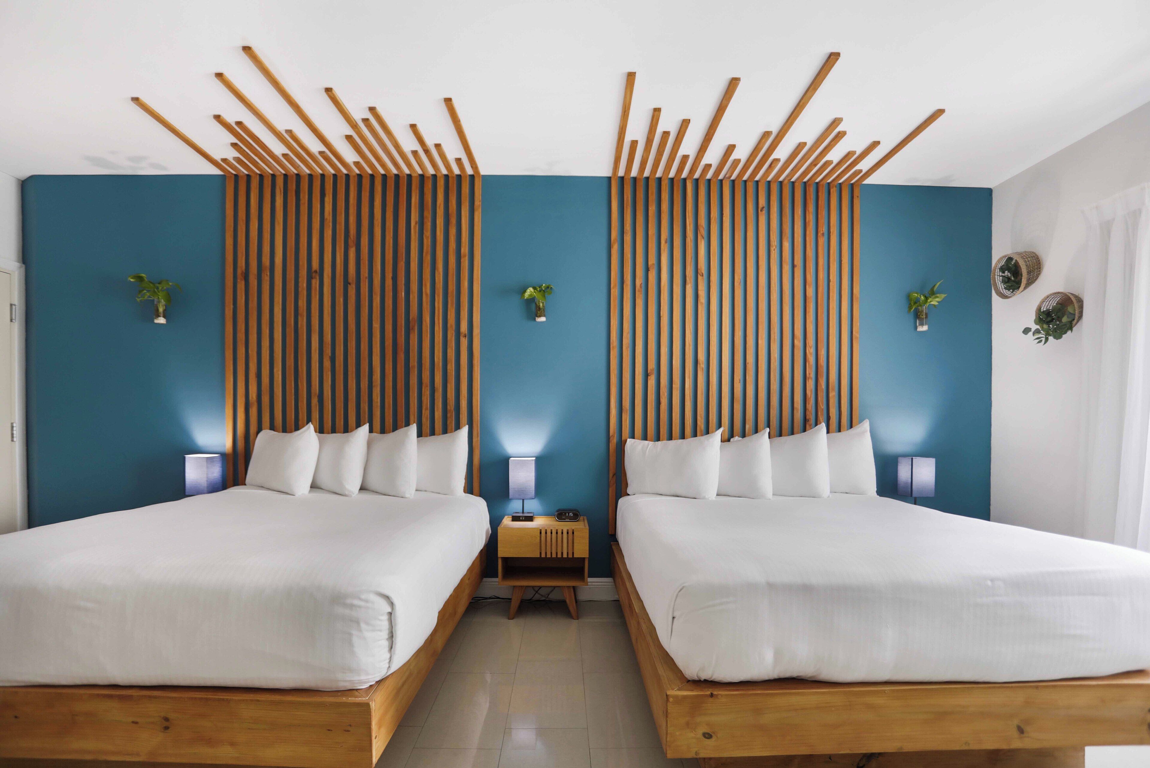 A room with two beds, wooden headboards, and blue walls.