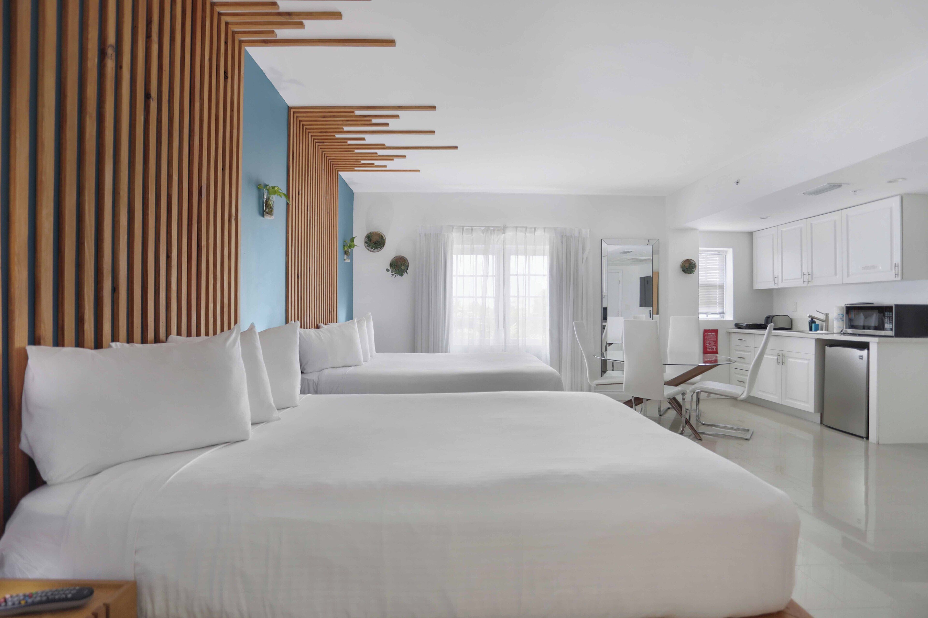 Ein Hotelzimmer mit zwei Betten, einer Küchenzeile und einem Badezimmer.