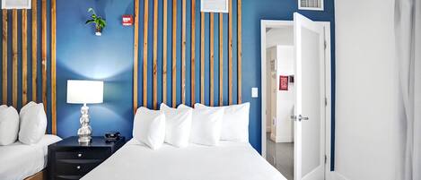 Ein Hotelzimmer mit Bett, Nachttisch, Lampe und einer Wand mit vertikalen Holzbalken.