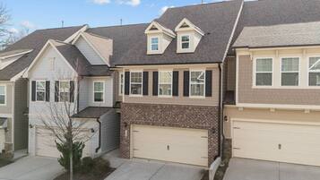 A two-story house with a garage, a small front yard, and a clear sky.