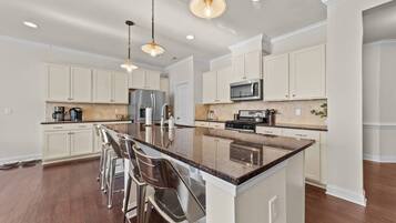 A modern kitchen with a large island, stainless steel appliances, and bar stools.