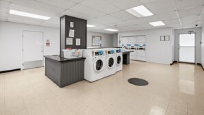 Un cuarto de lavandería con una estación de lavado central, un lavamanos y un tablón de anuncios.