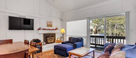 A living room with a wooden dining table, blue sofa, and a fireplace.