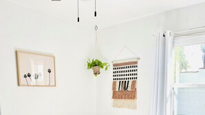 A bedroom with a bed, a hanging plant, a macrame wall hanging, and a framed picture. - Charming 1-bedroom house in lovely Mid-City Los Angeles (Los Angeles)