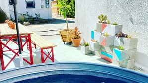 A swimming pool with a shark sculpture, surrounded by potted plants and a red table. - Charming 1-bedroom house in lovely Mid-City Los Angeles (Los Angeles)