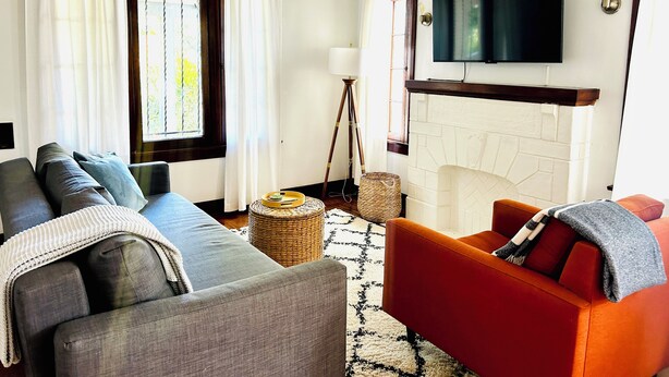 A living room with a sofa, armchair, and a fireplace. - Charming 1-bedroom house in lovely Mid-City Los Angeles (Los Angeles)