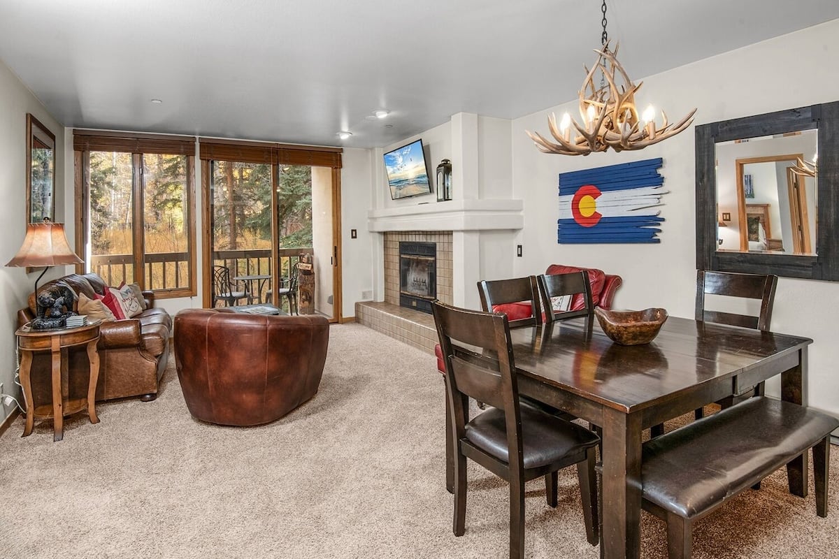 A dining area with a large wooden table, leather chairs, and a chandelier.