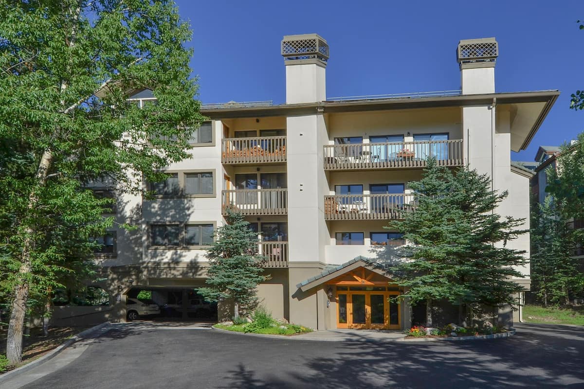 A multi-story hotel with balconies, a covered entrance, and a parking area.
